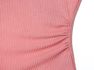 Close-up detail of light pink ribbed knit fabric with side drawstring ruched texture