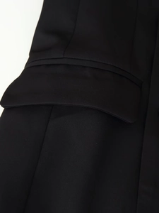 Vue détaillée de la poche à rabat du blazer noir avec coutures fines sur tissu texturé