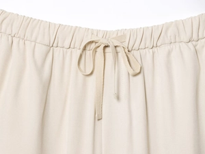 Detail of elastic waistband and adjustable drawstring on beige twill jogging pants