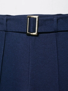 Detail of dark blue twill trousers featuring a minimalist golden rectangular waist buckle