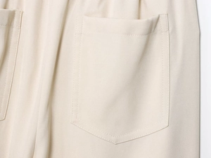 Macro shot of stitching detail and twill fabric texture on cream casual jogging pants