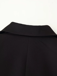 Détail d'un col de blazer en sergé noir montrant les coutures et la texture du tissu