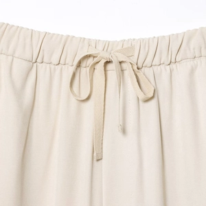 Close-up of beige elastic waist joggers with drawstring detail and twill fabric texture
