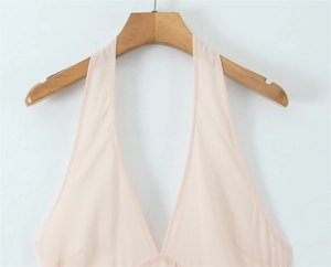 Detail of elegant skin-pink halter top with deep V-neckline on a wooden hanger