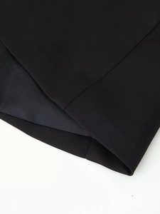 Gros plan du poignet de blazer noir montrant la texture du tissu et la doublure soyeuse