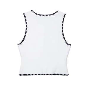 Close-up of knit fabric texture and black scalloped contrast piping on white vest