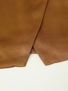 Detailed macro view of the double-breasted asymmetrical vest with fine brown fabric texture