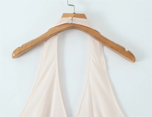 Detail of elegant halter neck dress with double button closure and open back design