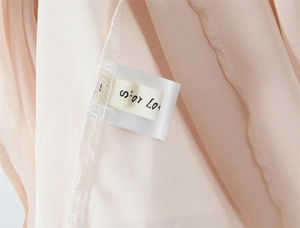 Macro view of stitching and size S label on a slim-fit elegant halter neck pink dress