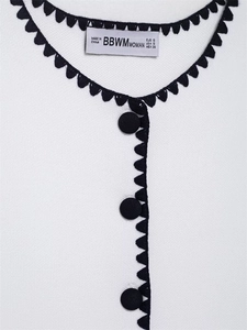 Detail of contrast stitch trim, black buttons and interior brand label on knit vest