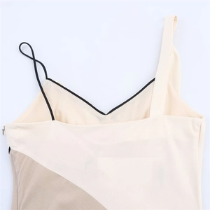 Detail of color-block dress featuring asymmetric straps and V-neckline with black trim