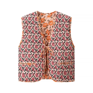 Détail d'un gilet matelassé fleuri avec ruban à nouer et doublure orange vif à l'intérieur