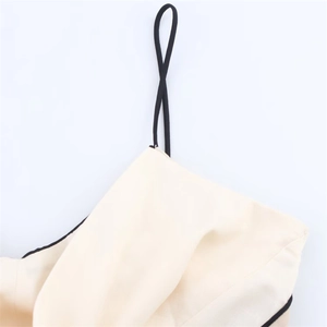Macro detail of beige dress fabric with thin black strap and contrast stitching