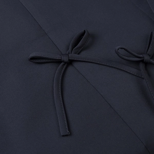 Detail of navy blue blazer featuring a stylish bow tie decorative design on smooth fabric