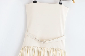 Detail of beige strapless dress featuring a belted waist and elegant pleated fabric texture