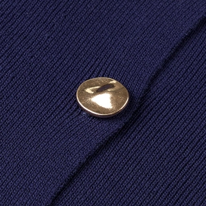 Macro shot of navy ribbed knit fabric featuring a unique irregular gold metal button