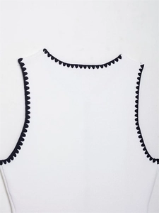 Detail of white sleeveless knit top with black scalloped embroidery on round neckline