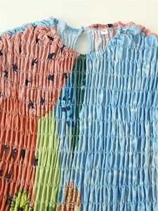 Detail of smocked fabric on a sleeveless dress with floral print and ruffled neckline
