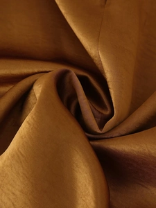 Close-up of bronze satin fabric texture showing smooth silk sheen and soft elegant folds