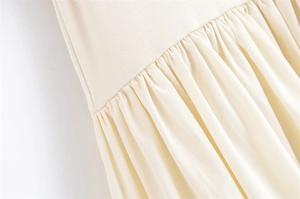 Detail of beige dress showing ribbed knit splicing and pleated fabric texture