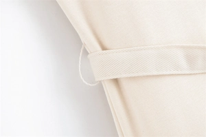 Macro detail of twill fabric texture and belt loop stitching on the off-white dress