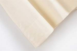 Macro shot of fine beige cotton fabric with clean single-needle stitching and soft texture
