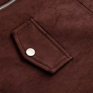 Détail macro d'une veste en suédine montrant le rabat de poche et le bouton en argent