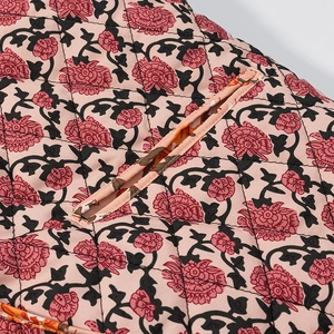 Gros plan sur tissu matelassé rose à imprimé floral et finition de bordure soignée