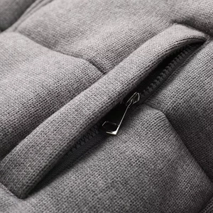 Macro detail of a grey knitted jacket featuring a silver zipper and quilted texture
