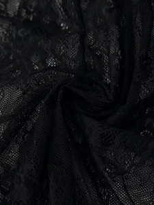 Vue détaillée du tissu en dentelle florale noire avec texture ajourée et drapé doux