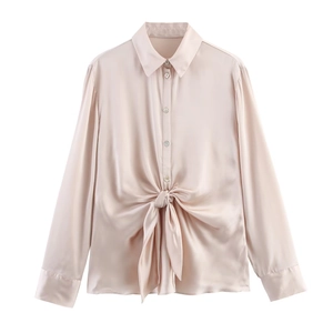 Detail of light pink satin shirt featuring long sleeves and unique waist knot design