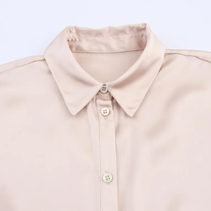 Close-up of champagne satin blouse collar with elegant mother of pearl buttons