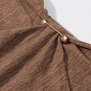Detailansicht von braunem Strickstoff und goldener Metallschnalle am ärmellosen Set