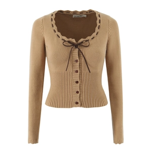 Dettaglio del cardigan in maglia cammello con scollo a balze e fiocco in pelle scura