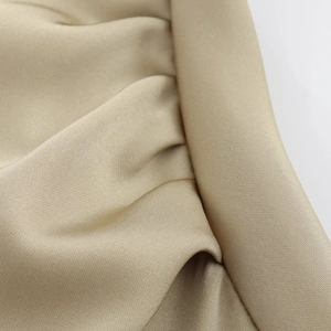 Close-up detail of champagne gold satin fabric texture with premium glossy silk finish