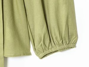 Detail of green blouse cuff featuring elastic ruffled edge and cotton linen texture
