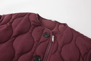 Detail der weinroten Steppjacke mit Rundhalsausschnitt und Knopf-Reißverschluss