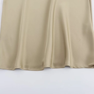Detailed view of champagne satin dress hem showing high-quality silk texture and stitching