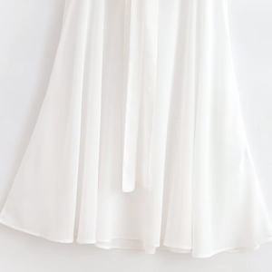 Close-up of white summer dress featuring elegant pleated waist and drapery fabric texture