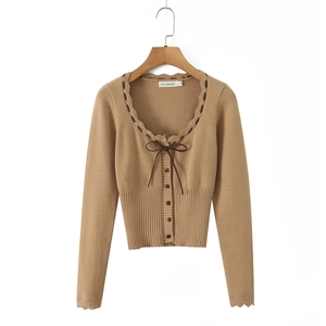 Dettaglio del cardigan in maglia con bordi a volant, scollo a U e fiocco sottile