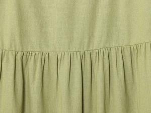 Detail of green linen blouse showing premium fabric texture and pleated ruffles