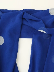 Gros plan du tissu de robe en mousseline bleu roi avec imprimé à pois blancs
