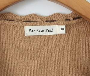 Dettaglio macro dello scollo di un maglione in maglia marrone con bordi a conchiglia