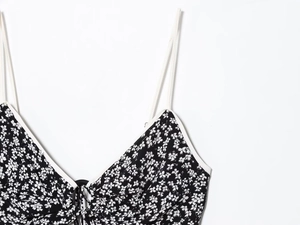 Detail of floral dress neckline with black floral pattern, white piping and lace-up straps