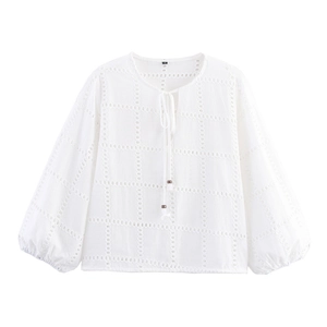 Dettaglio della camicia bianca a maniche lunghe con ricamo traforato e nappe