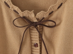 Dettaglio del cardigan in maglia cammello con scollo a balze e fiocco di velluto