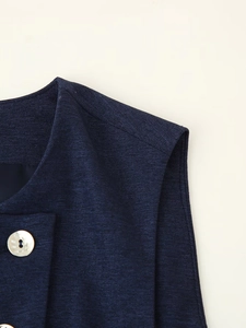Détail du gilet bleu marine montrant la texture tissée et un bouton en nacre brillant
