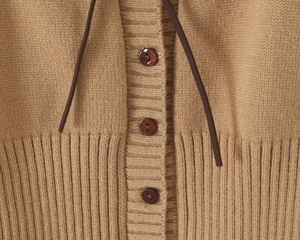 Dettaglio del cardigan in maglia kaki con bottoni marroni e cordoncino decorativo