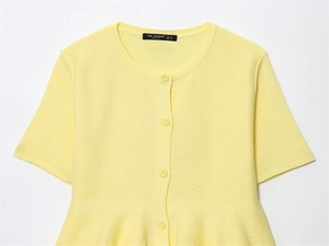 Close-up of pale yellow short-sleeve knit cardigan with buttons and peplum hem details