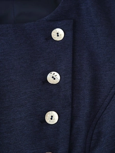 Vue détaillée du tissu bleu foncé texturé avec trois boutons dorés à effet martelé